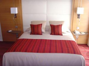 a large bed with red pillows in a hotel room at Le Churchill Hôtel & Spa in Carnac