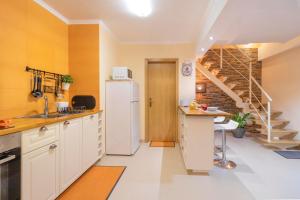 a kitchen with a white refrigerator and a staircase at Casinha da Lurdes in Sesimbra