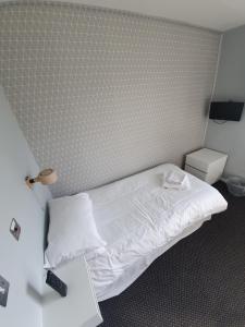 um quarto com uma cama com lençóis brancos e um candeeiro em The Derby Conference Centre - Shared Accomodation em Derby