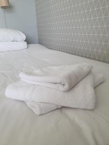 uma pilha de toalhas brancas sentadas numa cama em The Derby Conference Centre - Shared Accomodation em Derby