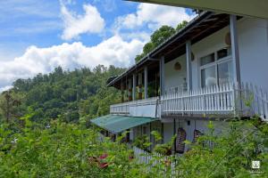 uma casa branca com varanda e árvores em Villa Perpetua em Bandarawela