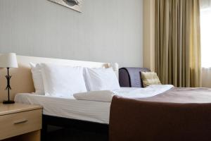 a bedroom with a bed with white sheets and pillows at Atlantic by USTA Hotels in Yekaterinburg