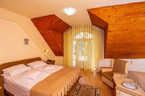 a bedroom with a bed and a couch and a window at Hotel Castel in Sfântu-Gheorghe