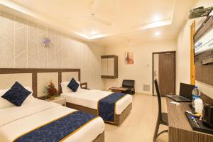 a hotel room with two beds and a desk at Hotel Sheetal Plaza in Surat
