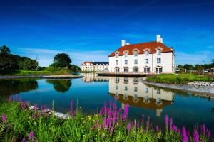 um edifício branco com um telhado vermelho ao lado de um lago em Staycity Aparthotels near Disneyland Paris em Bailly-Romainvilliers