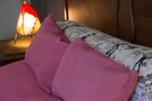 2 almohadas rosas en una cama junto a una lámpara en B and B Comme chez soi en La Hestre