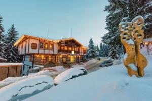 a house in the snow with snow covered roofs at MPM Family Hotel Merryan in Pamporovo
