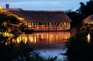 un grande edificio con tetto di paglia su un lago di Premier Resort Mpongo Private Game Reserve a Macleantown