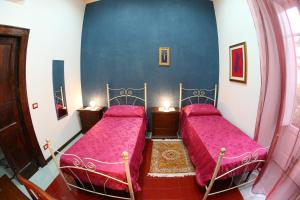 two beds in a room with pink sheets at Casa Lissania in Lamezia Terme