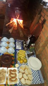 a table with plates of food and a fireplace at Aconchego Caminho das Cachoeiras in Rio Acima