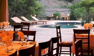a dining table with chairs and a swimming pool at Premier Resort Mpongo Private Game Reserve in Macleantown