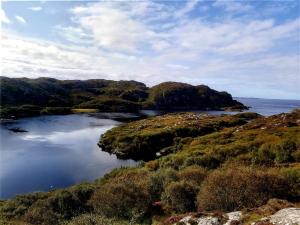 a view of a body of water with mountains and the ocean at Achmelvich View self catering in Lochinver