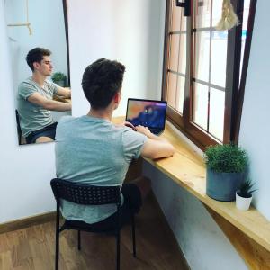 a man sitting at a desk with a laptop computer at Columbus Apartments Co-Living in Las Palmas de Gran Canaria