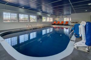 a large swimming pool with blue water and orange chairs at Westbridge Inn and Suite in Centerville