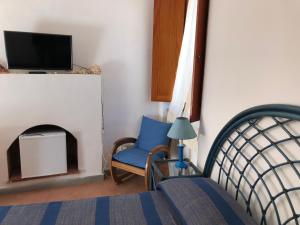 a bedroom with a bed and a chair and a tv at STANZA INDIPENDENTE SUPER ARREDATA CENTRALE E LUMINOSISSIMA in Rio nellʼElba
