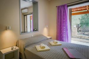 a bedroom with a bed and a window with purple curtains at Aggerikos Relax House in Ayios Kirikos