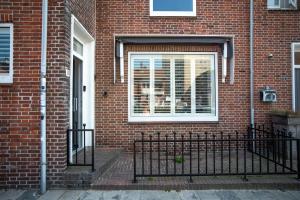 a brick house with a window and a fence at Bamboa Beachhouse in Zandvoort +9 photos