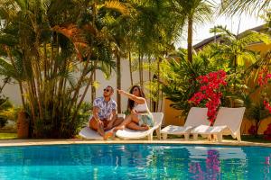 a man and woman sitting next to a swimming pool at Pousada Porto Azul in Cumbuco