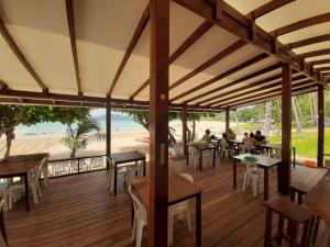 people sitting at tables on a deck with a view of the beach at Duli Beach Resort in El Nido