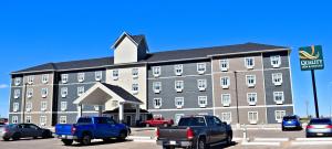 a large building with cars parked in front of it at Quality Inn & Suites in Moose Jaw