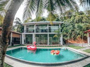 a swimming pool with two inflatable flamingos in front of a house at Green Hill Mirissa in Mirissa