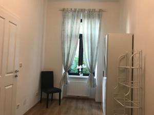 Zimmer mit einem Fenster mit einem schwarzen Stuhl und einem schwarzen Stuhl in der Unterkunft Imperial Apartments Schönbrunn - Jadengasse in Wien