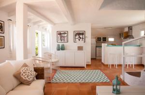 a living room with a white couch and a kitchen at San Colomban in Sant Lluis