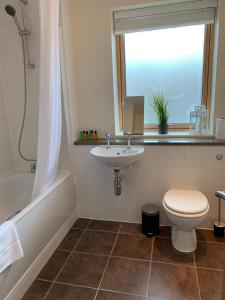 a bathroom with a sink and a toilet and a window at Three Bedroom Townhouse with Parking in Telford