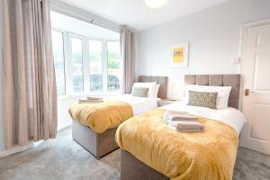 two beds in a room with a window at Spacious house in Swansea TV in every bedroom in Swansea