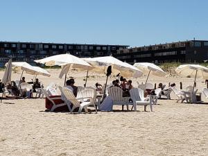 un grupo de personas sentadas en la playa bajo sombrillas en Linda Bay Premium Resort en Mar de las Pampas