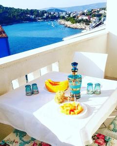 a white table with a plate of fruit on it at Apartments Goja in Ražanj