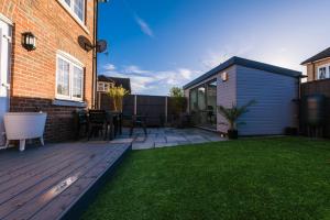 a backyard with a wooden deck and a house at Riverside Stays, Modern House Stays, Shefford, Bedfordshire in Shefford