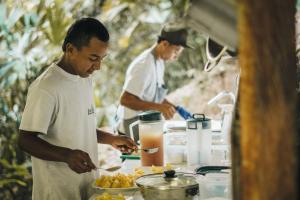 Doradal的住宿－El Tigrillo Rio Claro by Los Colores Ecoparque，两个男人在食品车里准备食物