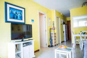 a living room with a flat screen tv and yellow walls at Acogedor apartamento en primera linea de playa in Salou