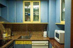 a kitchen with blue cabinets and a sink and a microwave at Acogedor apartamento en primera linea de playa in Salou