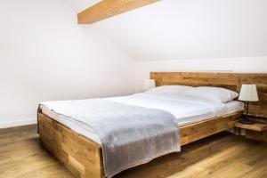 a bedroom with a large wooden bed with white sheets at Maya Pokoje i Apartamenty in Karpacz