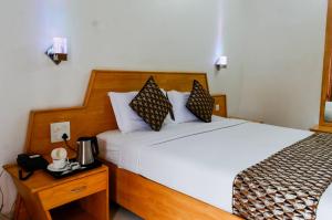 a hotel room with a bed and a nightstand with a bed sidx sidx sidx at OPALO Kailas Kovalam in Kovalam