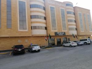 un gran edificio con coches estacionados en un estacionamiento en Arif Housing Units, en Buraidah