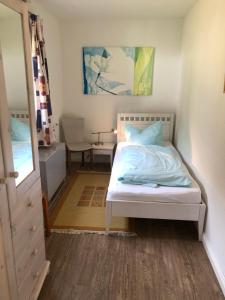 Schlafzimmer mit einem weißen Bett und einem Spiegel in der Unterkunft Bungalow 3 in Wyk auf Föhr