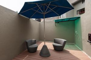 a patio with two chairs and a blue umbrella at Cuarto en las Lomas in Mexico City