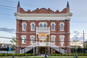 a large red brick building with a white balcony at Sonder Gravier Place in New Orleans