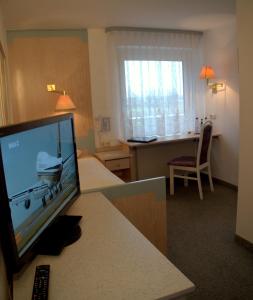 a hotel room with a flat screen tv and a bedroom at Best Breakfast - Hotel Justina in Bad Wörishofen