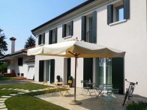 a white house with a table and an umbrella at Le Mandragole B&B in Roncade