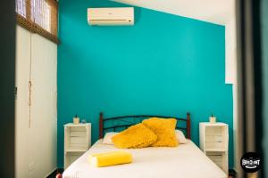 un oso de peluche amarillo sentado en una cama con una pared azul en The Corner Hostel en Playa Blanca