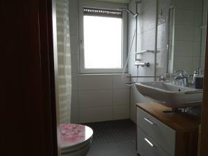 a bathroom with a sink and a toilet and a window at Helle Ferienwohnung in Nettetal bei Venlo in Nettetal