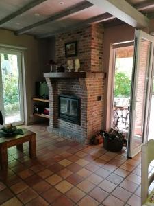 a living room with a brick fireplace with two windows at Rainbow Lodge in Ursel