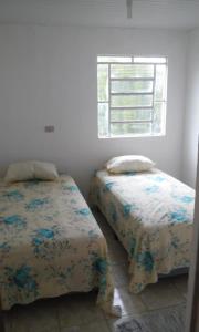 two beds in a white room with a window at CHÁCARA SANTA TERESA in Triunfo