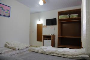 a bedroom with two beds and a tv in it at Pousada Vila Rica in Cunha