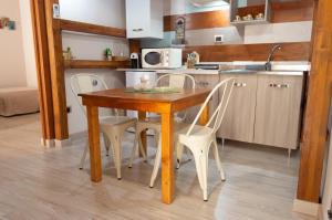 cocina con mesa de madera y sillas blancas en La Suite del Vicolo en Agrigento