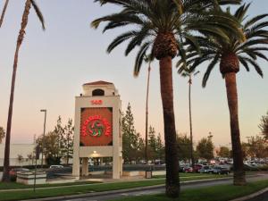 a clock tower in a parking lot with palm trees at Valley Hotel in Rosemead